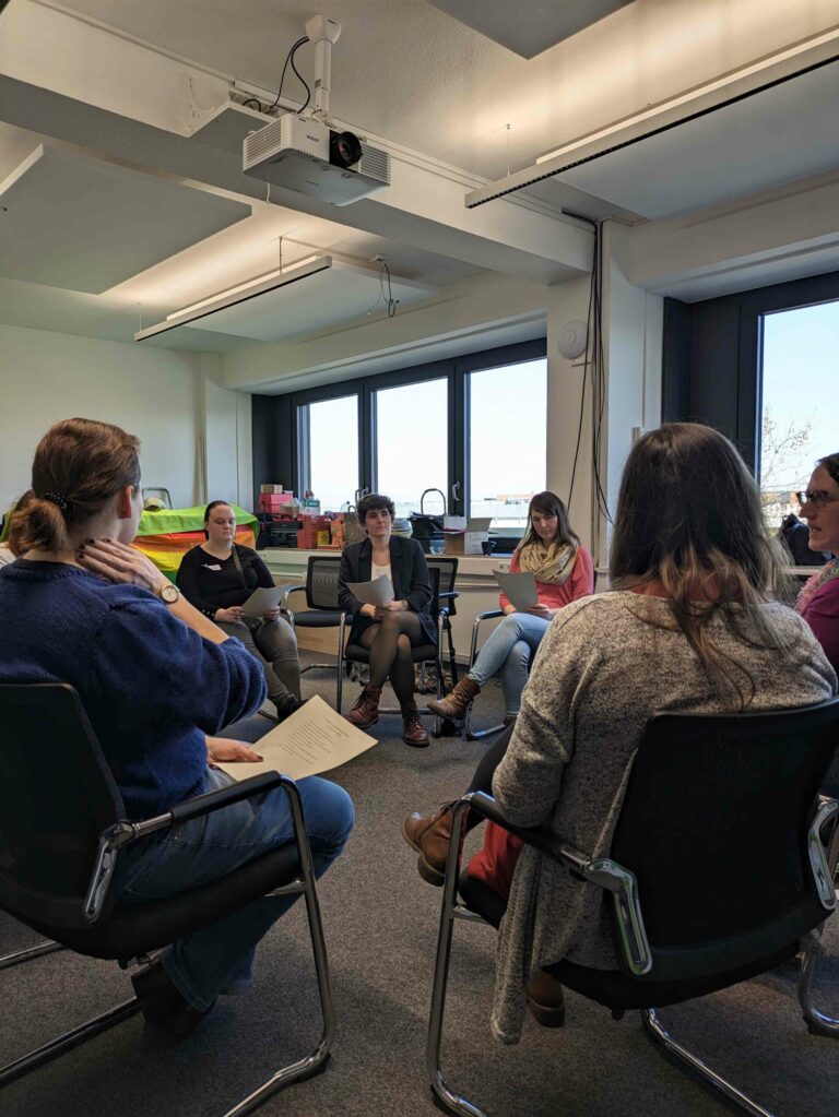 Eine Gruppe von Menschen sitzt in einem Stuhlkreis und redet.