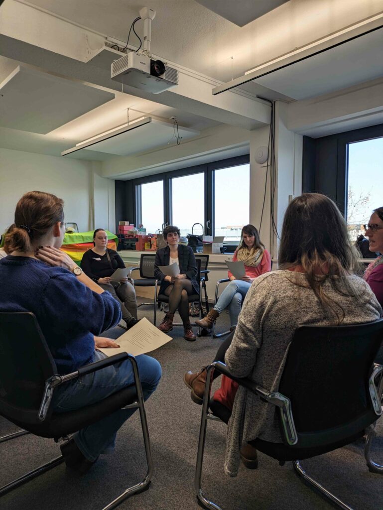 Eine Gruppe von Menschen sitzt in einem Stuhlkreis und redet.